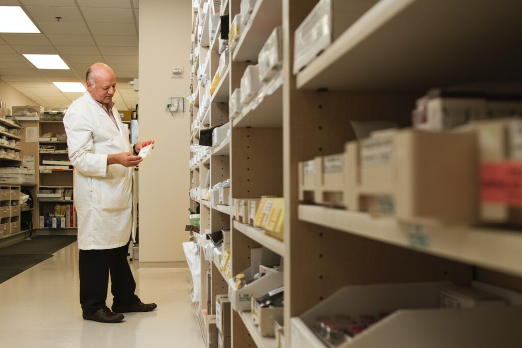 woman in white dress shirt and black pants standing near brown wooden shelf gerenciamento hospitalar